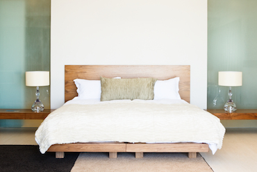 a room with a low, two-person bed, with shelves built into the walls holding a lamp on each side of the bed